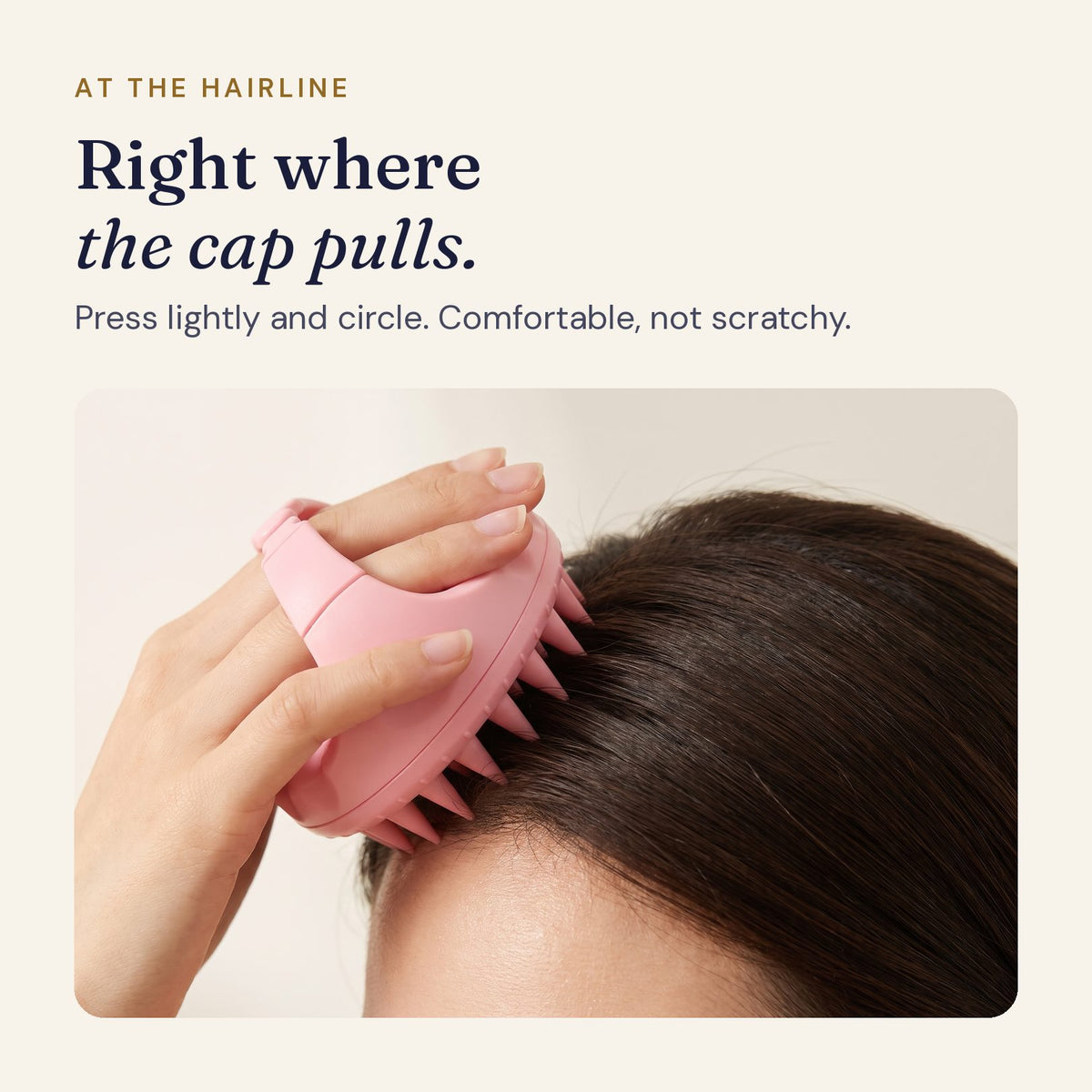 Hand holding the pink scalp massager at the front hairline by the temple